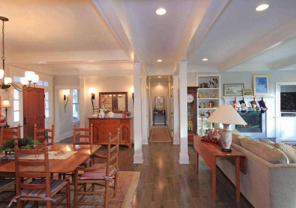 dining and living area with hardwood floors, white coffered ceilings, and fireplace decorated with Christmas stockings.